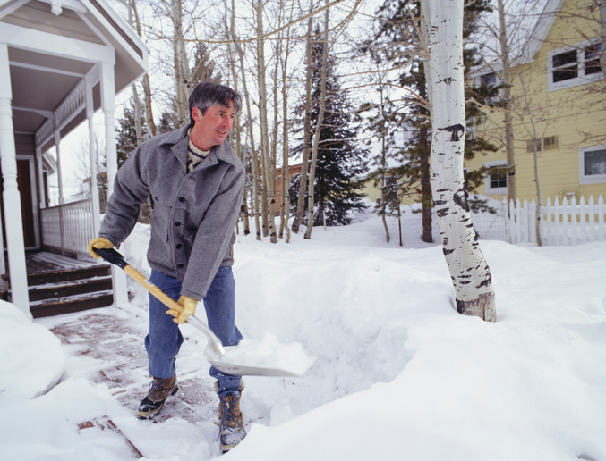 Man shovelling snow from walkway outside house