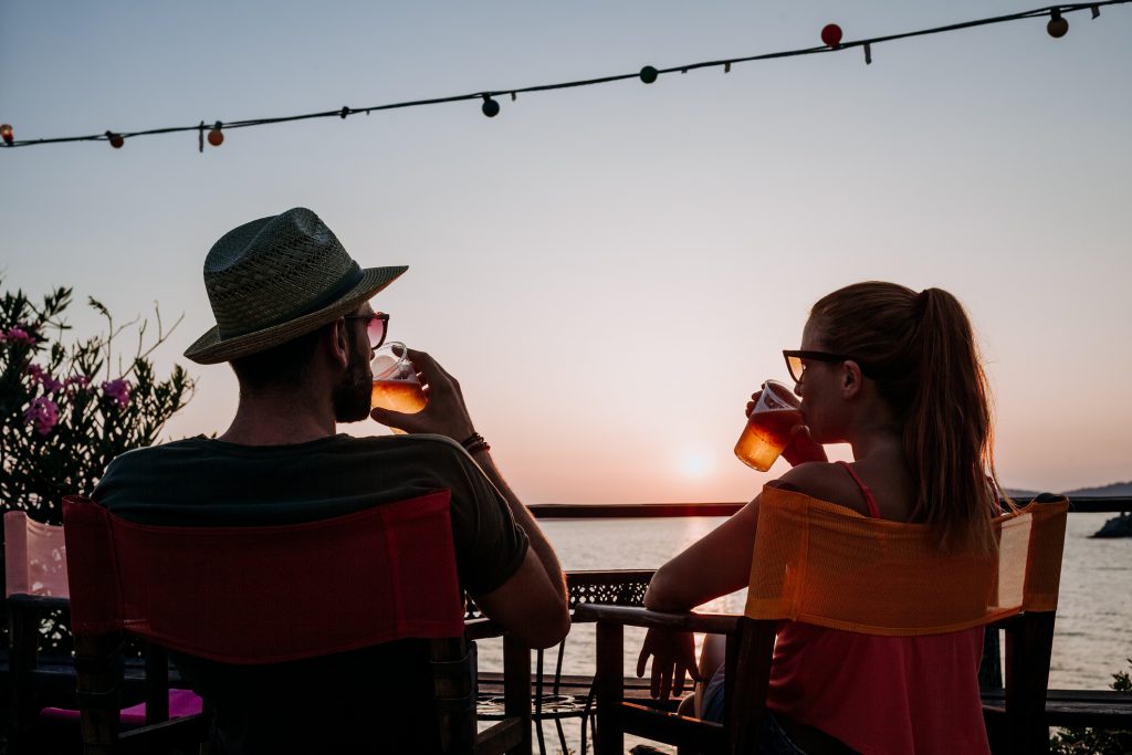 Young couple enjoying beer and sunset in a beach bar