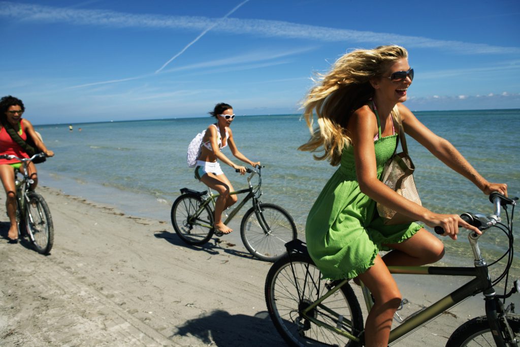 Three women riding bikes on the beach