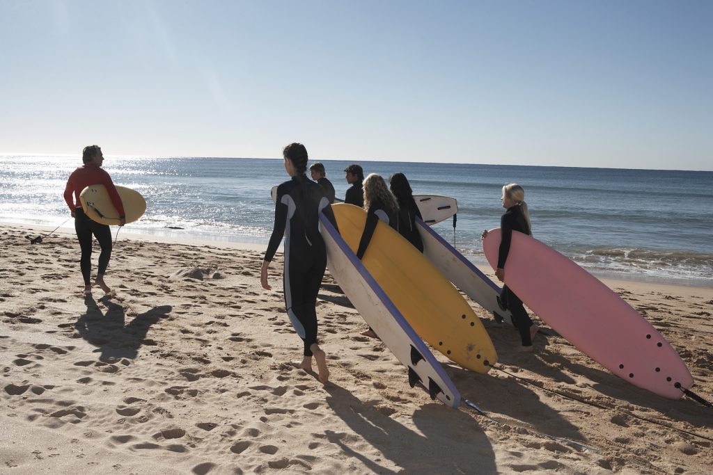 a group of teenagers along with an instructor learning how to surf at the beach