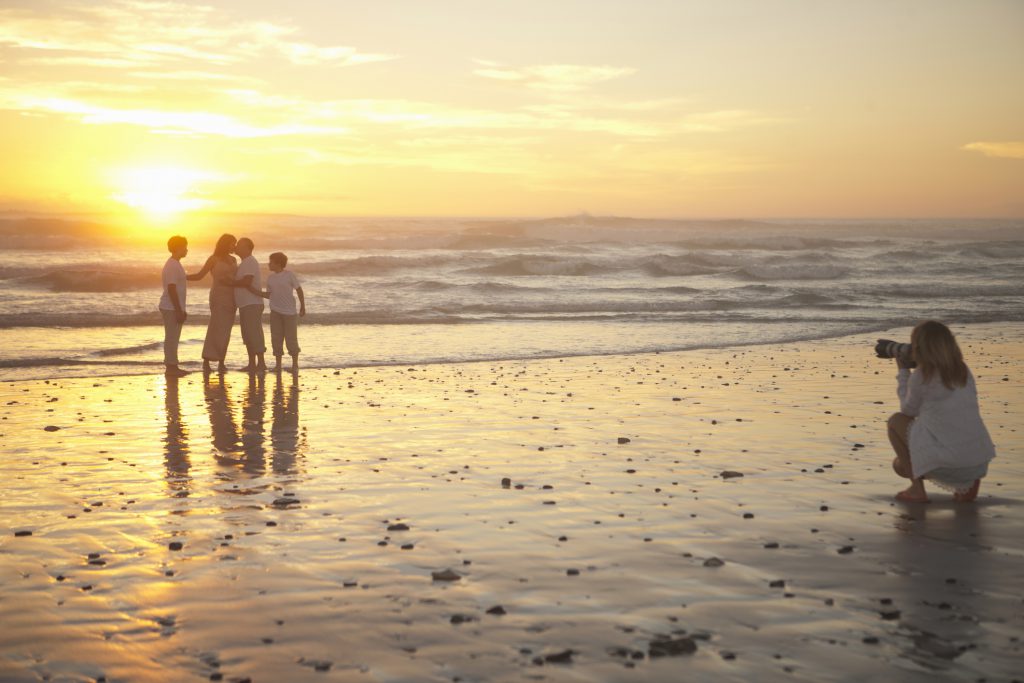 family getting photographed by a photographer during golden hour on the beach